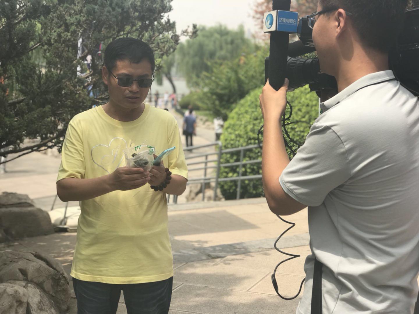 領(lǐng)到荷葉粽的市民心情激動(dòng)地接受電視臺(tái)采訪